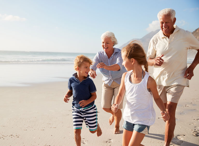 Grand-parents running on beach with grand-children